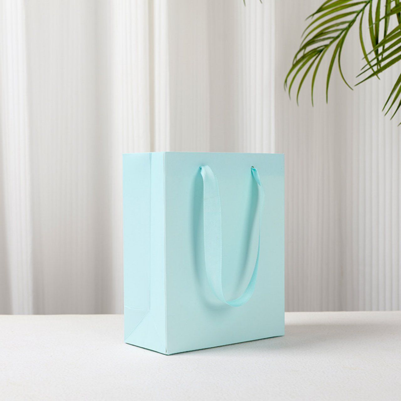 Blue paper shopping bag with ribbon handles
